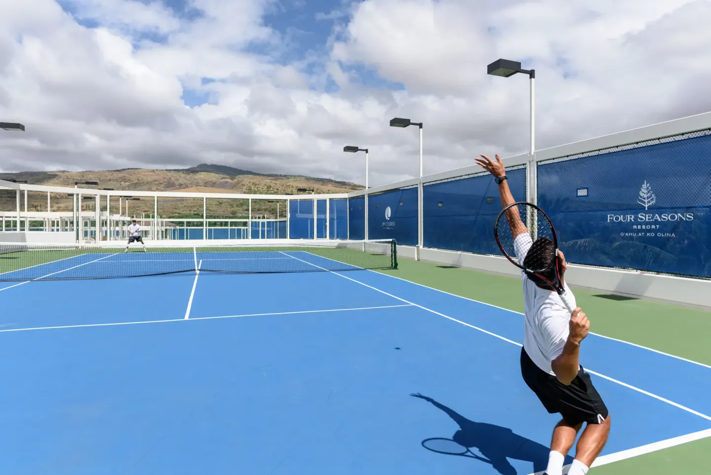 Tennis players on a blue outdoor court at Four Seasons Resort Oahu at Ko Olina.