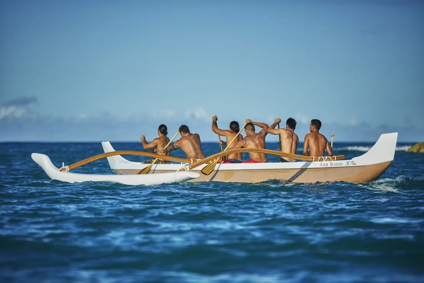Paddlers row an outrigger canoe on the ocean at Four Seasons Resort Oahu at Ko Olina.