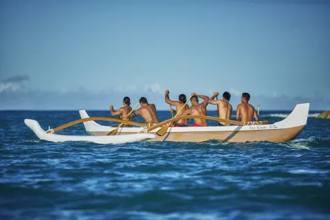 Paddlers row an outrigger canoe on the ocean at Four Seasons Resort Oahu at Ko Olina.