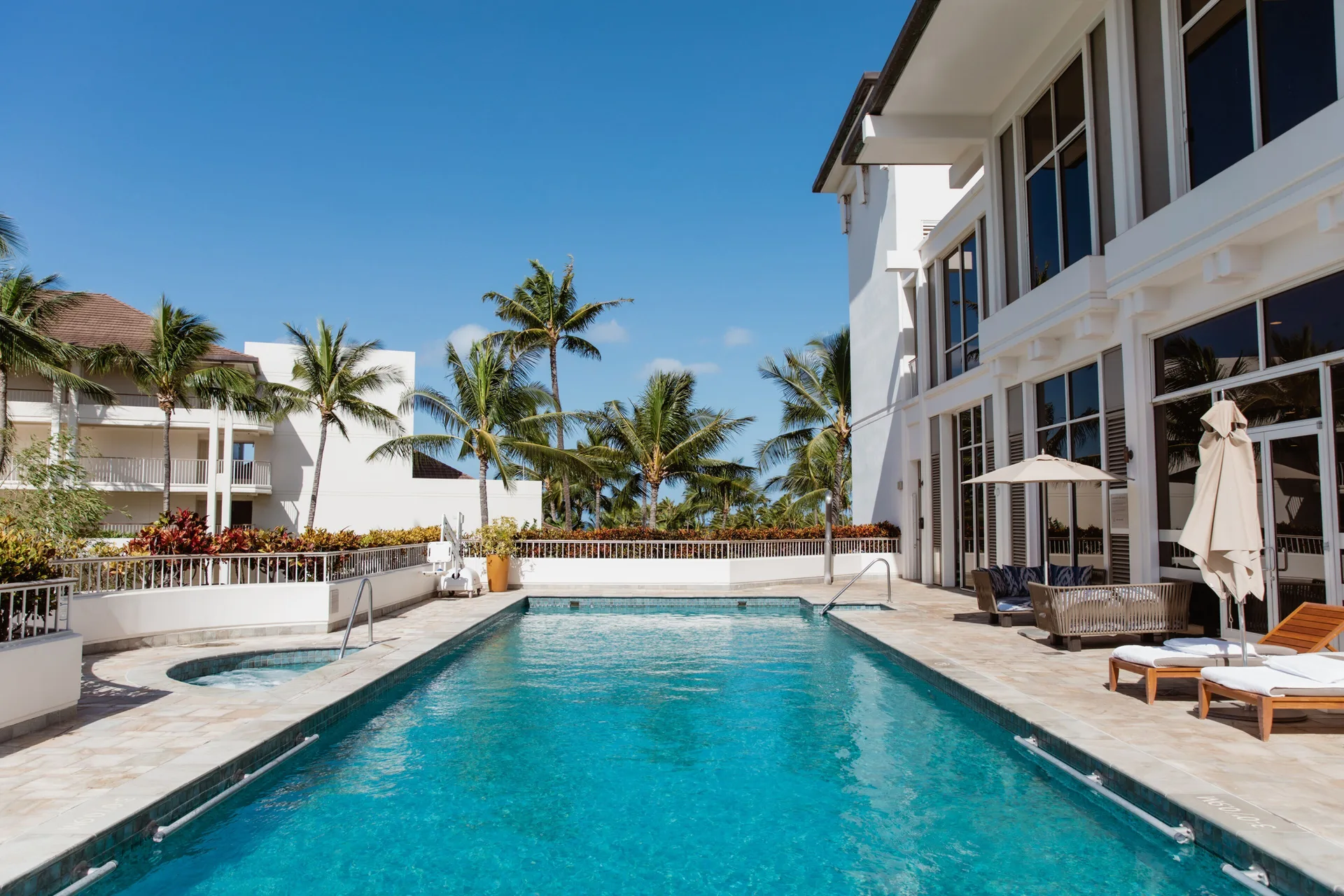 Quiet lap pool with loungers and palm trees at Four Seasons Resort Oahu at Ko Olina.