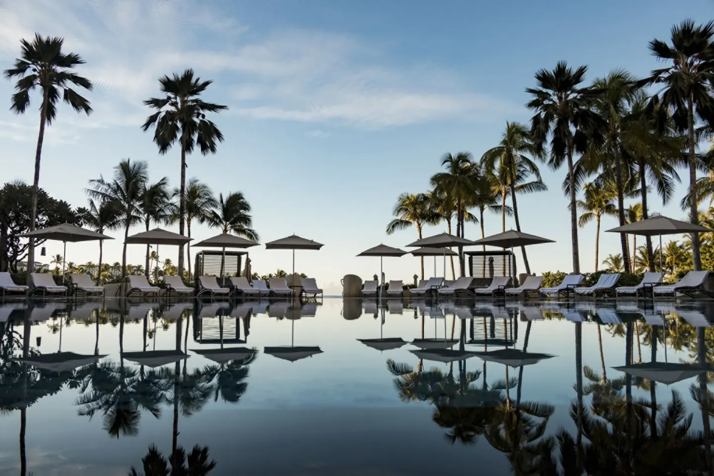 Reflecting pool with umbrellas and palms at Four Seasons Resort Oahu at Ko Olina.