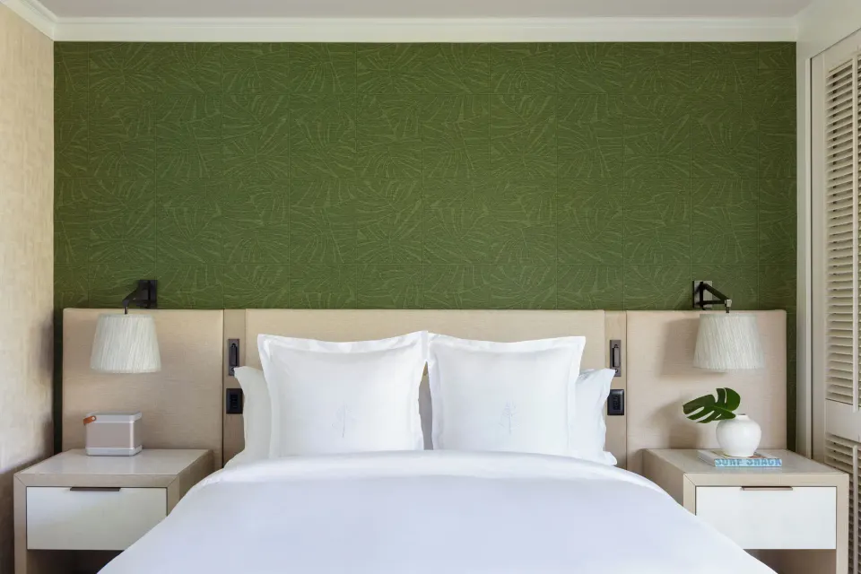 Club Resort Room bed with green accent wall at Four Seasons Resort Oahu at Ko Olina.
