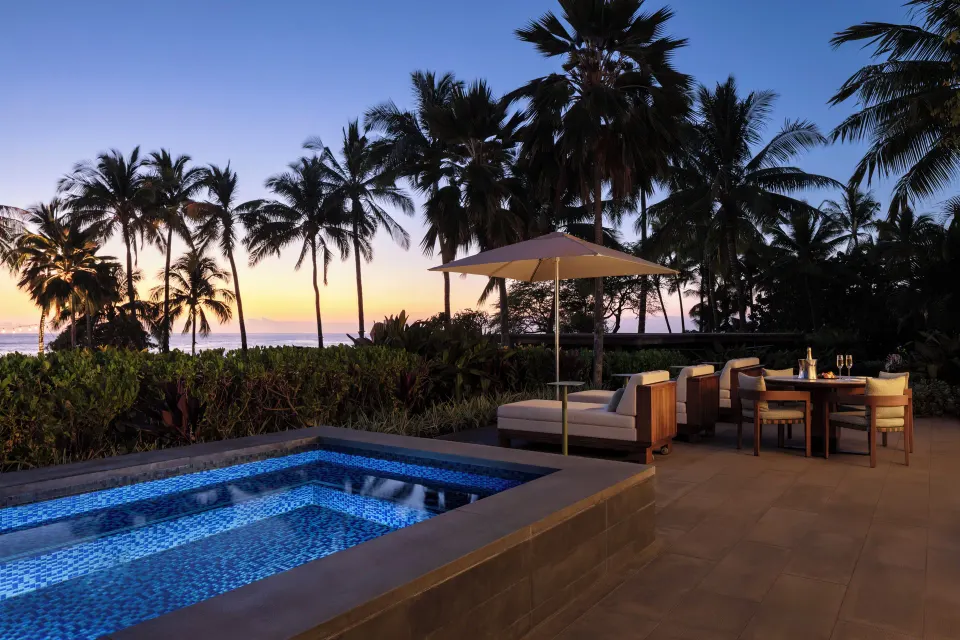 Pacific Suite terrace at Four Seasons Resort Oahu at Ko Olina with lit plunge pool at sunset.
