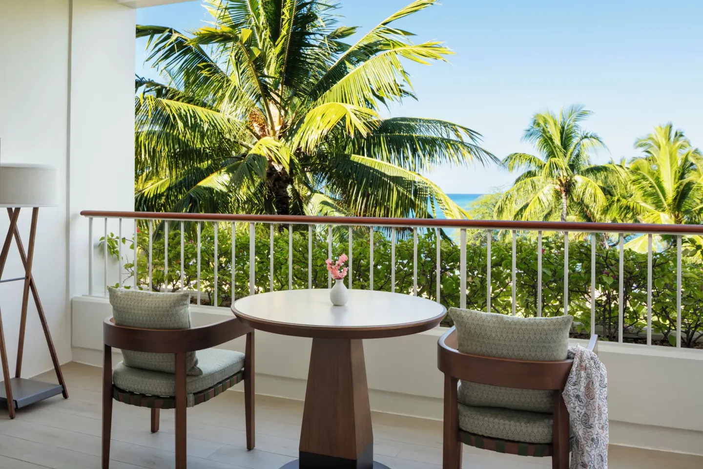 Partial Ocean Room balcony seating with palm and ocean view at Four Seasons Resort Oahu at Ko Olina.