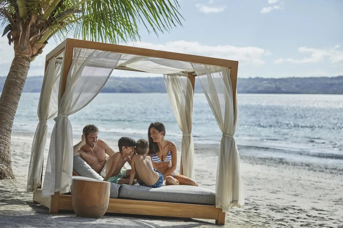 Family relaxing in a beach cabana at Four Seasons Resort Peninsula Papagayo, Costa Rica.