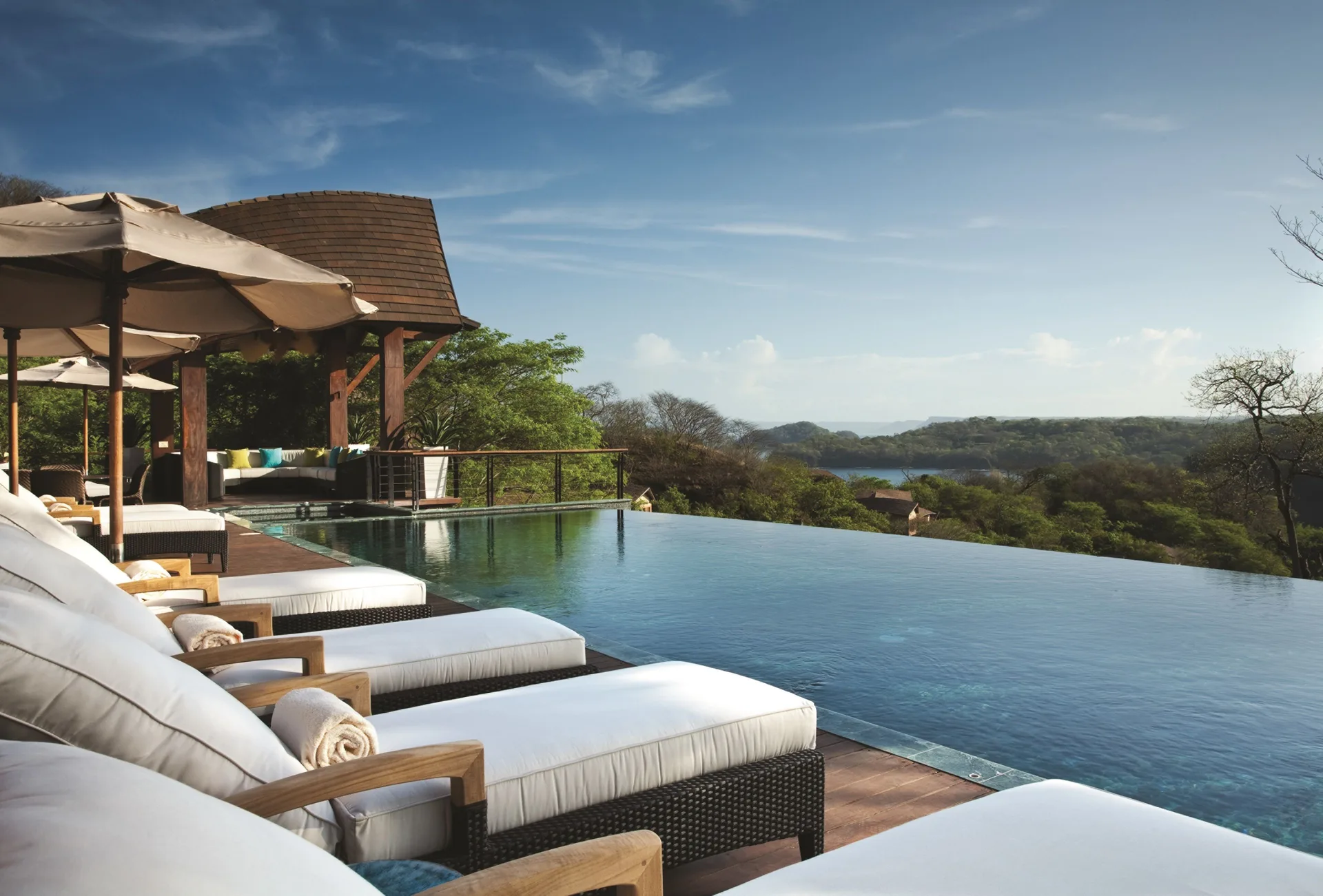 Infinity pool with cushioned loungers at Four Seasons Resort Peninsula Papagayo, Costa Rica.