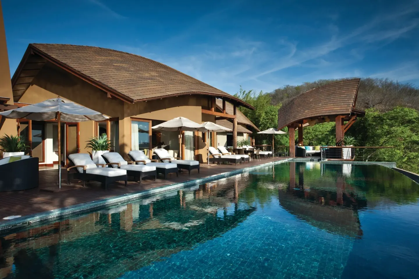 Pool terrace with lounge chairs and umbrellas at Four Seasons Resort Peninsula Papagayo, Costa Rica.