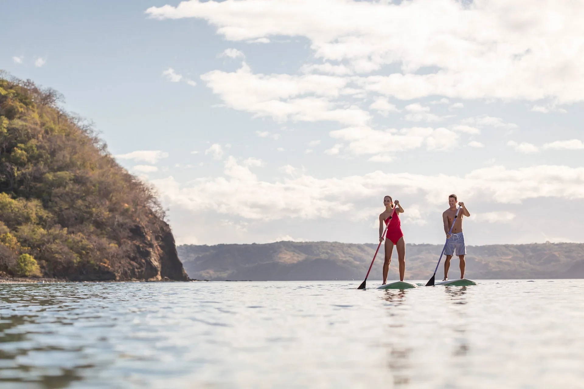 Two paddleboarders on calm bay water at Four Seasons Resort Peninsula Papagayo, Costa Rica.