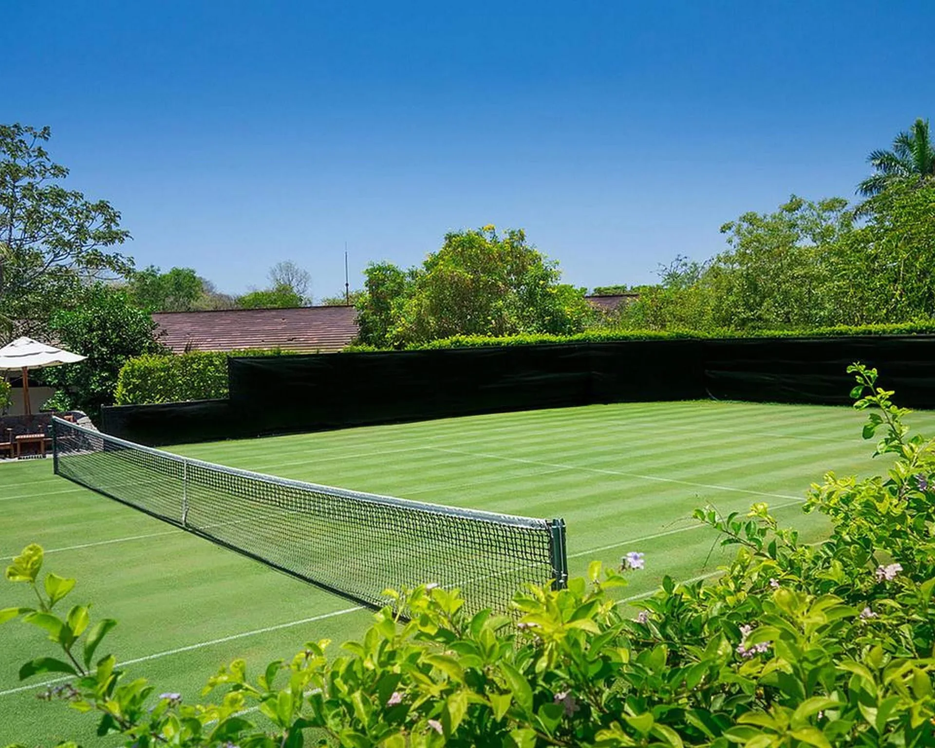 Green tennis court surrounded by hedges at Four Seasons Resort Peninsula Papagayo, Costa Rica.