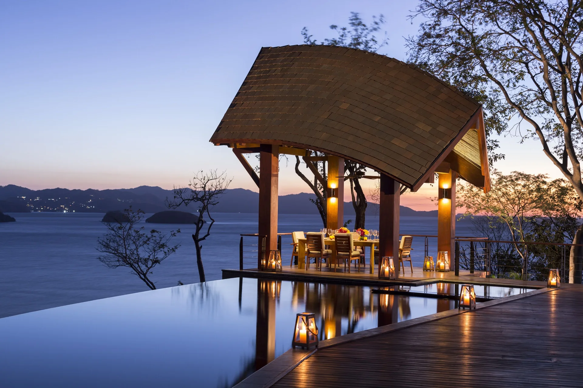 Lantern-lit dining pavilion by an infinity pool at Four Seasons Resort Peninsula Papagayo, Costa Rica.