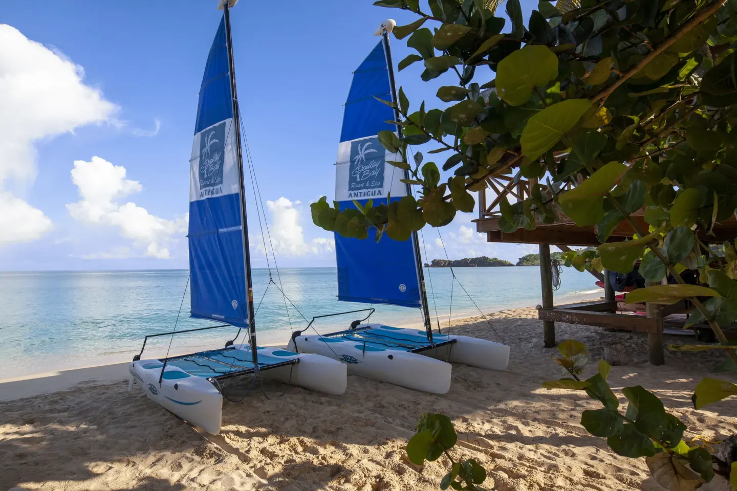 Two beach catamarans with blue sails on the sand at Galley Bay Resort & Spa.