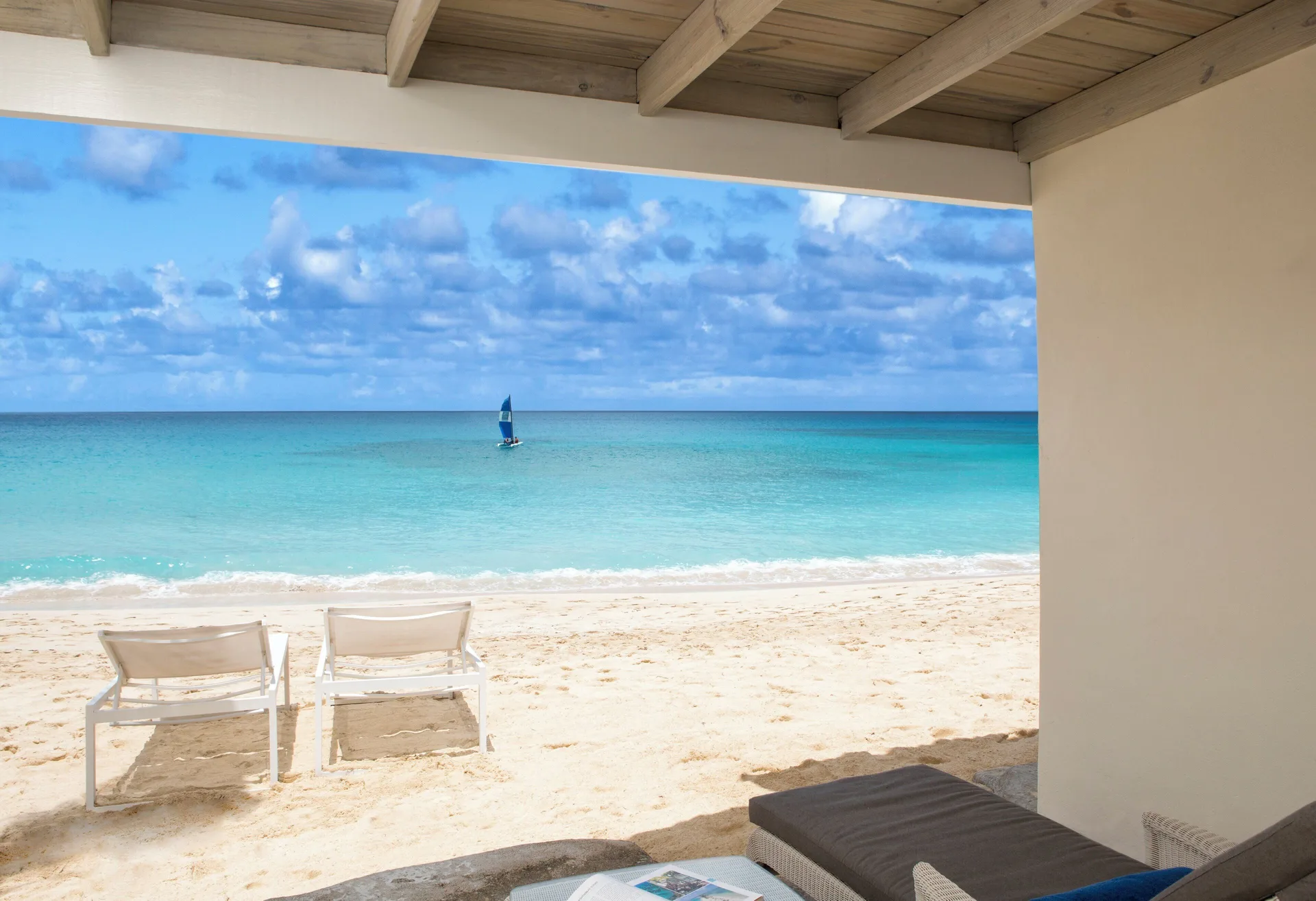 Beachfront patio with loungers and turquoise sea at Galley Bay Resort & Spa.