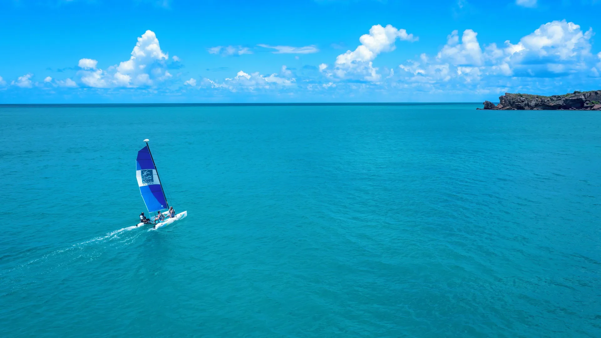 A catamaran sails across turquoise water near Galley Bay Resort & Spa.