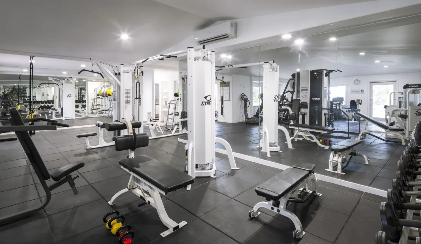 Mirrored fitness center with benches, cable machines, dumbbells, and kettlebells at Galley Bay Resort & Spa.