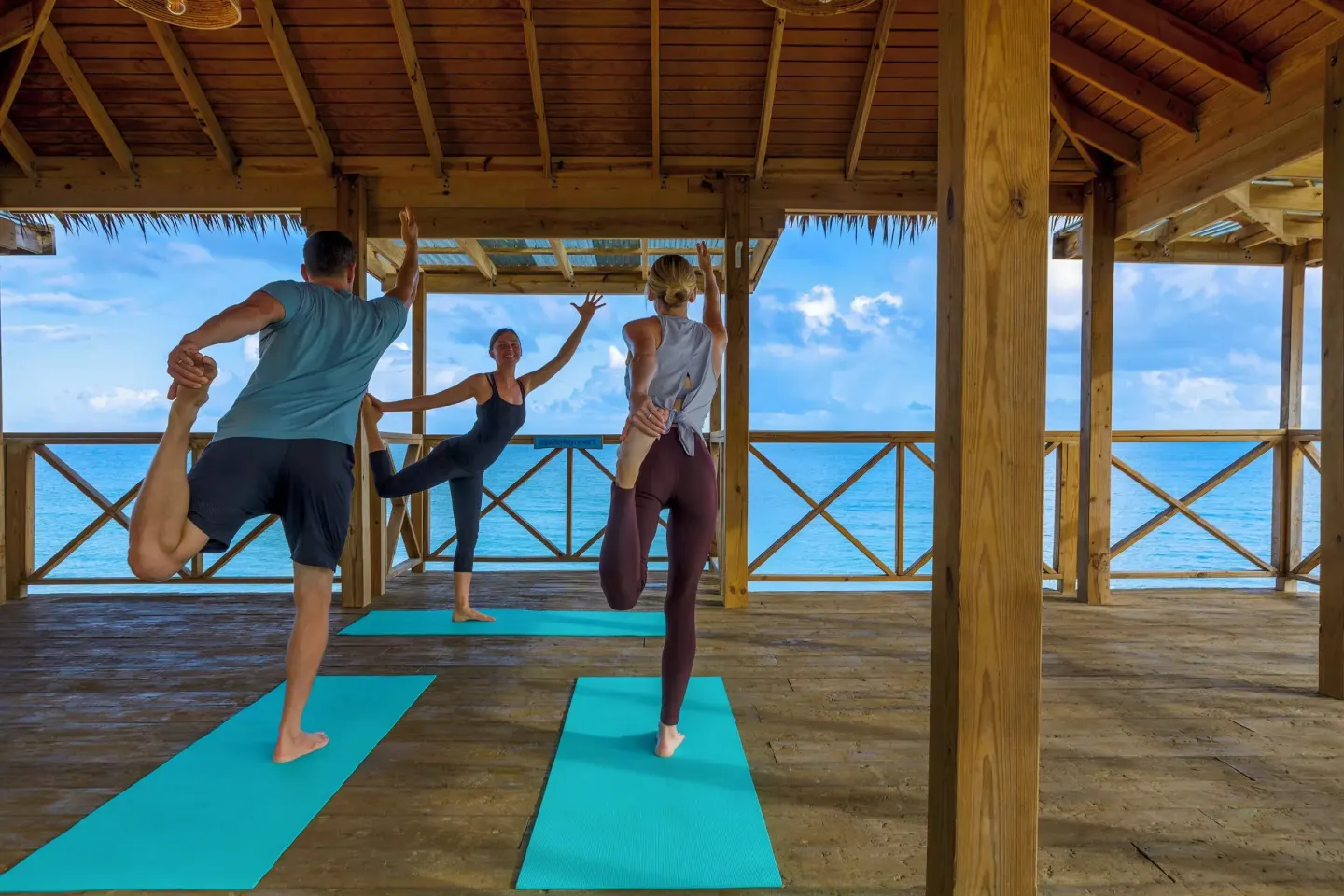 Small yoga class stretching on an open-air oceanfront deck at Galley Bay Resort & Spa.