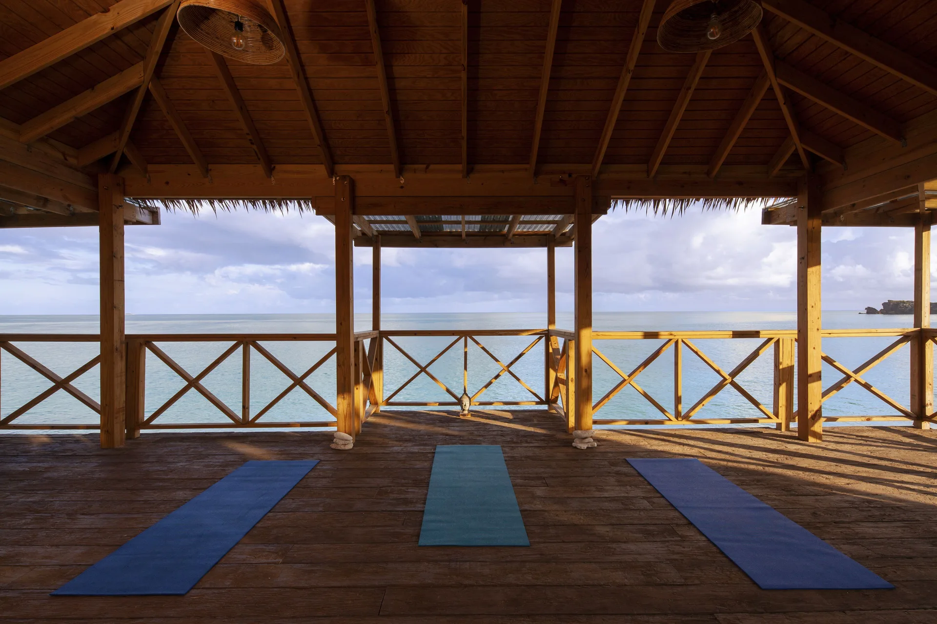 Open-air wooden yoga deck with mats facing the ocean at Galley Bay Resort & Spa.