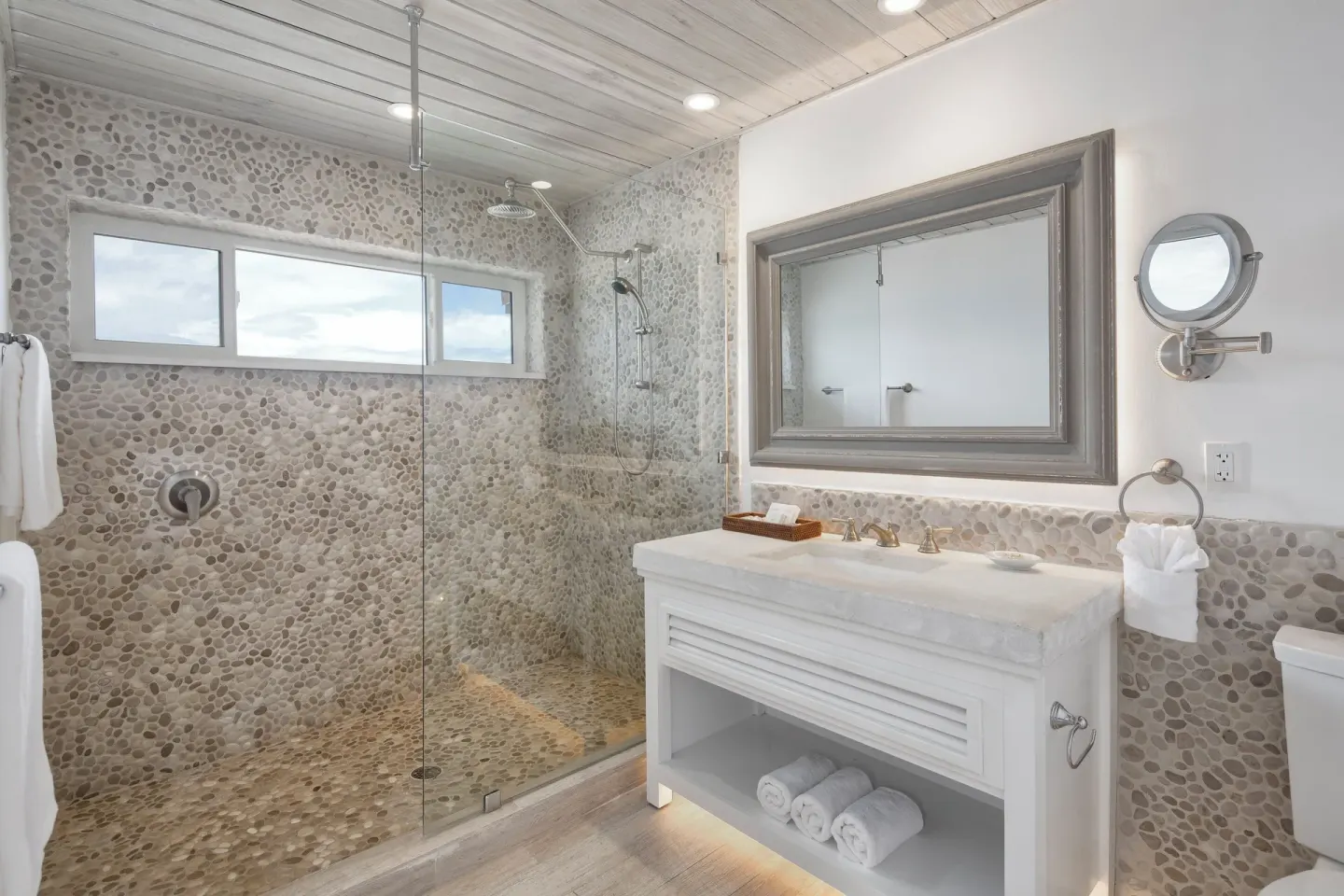 Pebble-tile bathroom with glass shower and vanity at Galley Bay Resort & Spa.