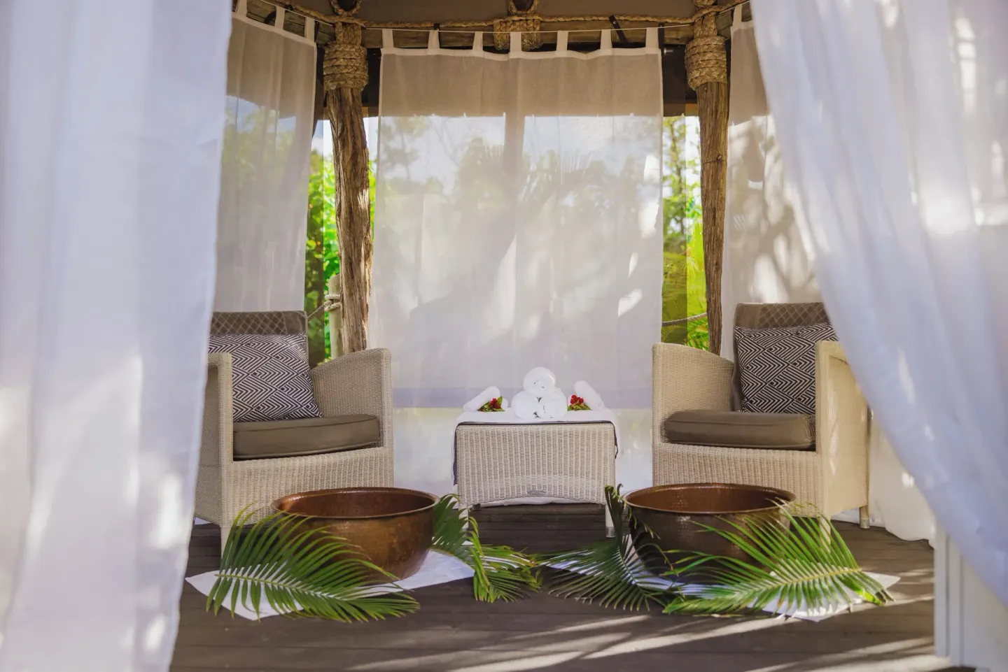 Spa seating nook with foot bowls and sheer curtains at Galley Bay Resort & Spa.