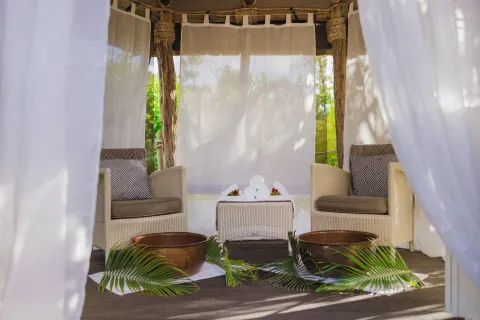 Spa seating nook with foot bowls and sheer curtains at Galley Bay Resort & Spa.