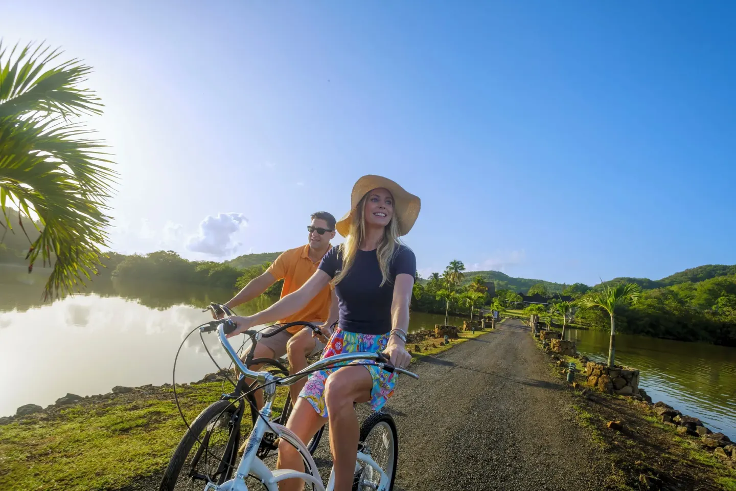 Guests cycling beside the lagoon under a blue sky at Galley Bay Resort & Spa.