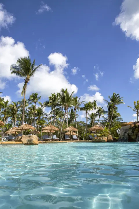 Swimming pool with palms, loungers and thatched umbrellas at Galley Bay Resort & Spa.