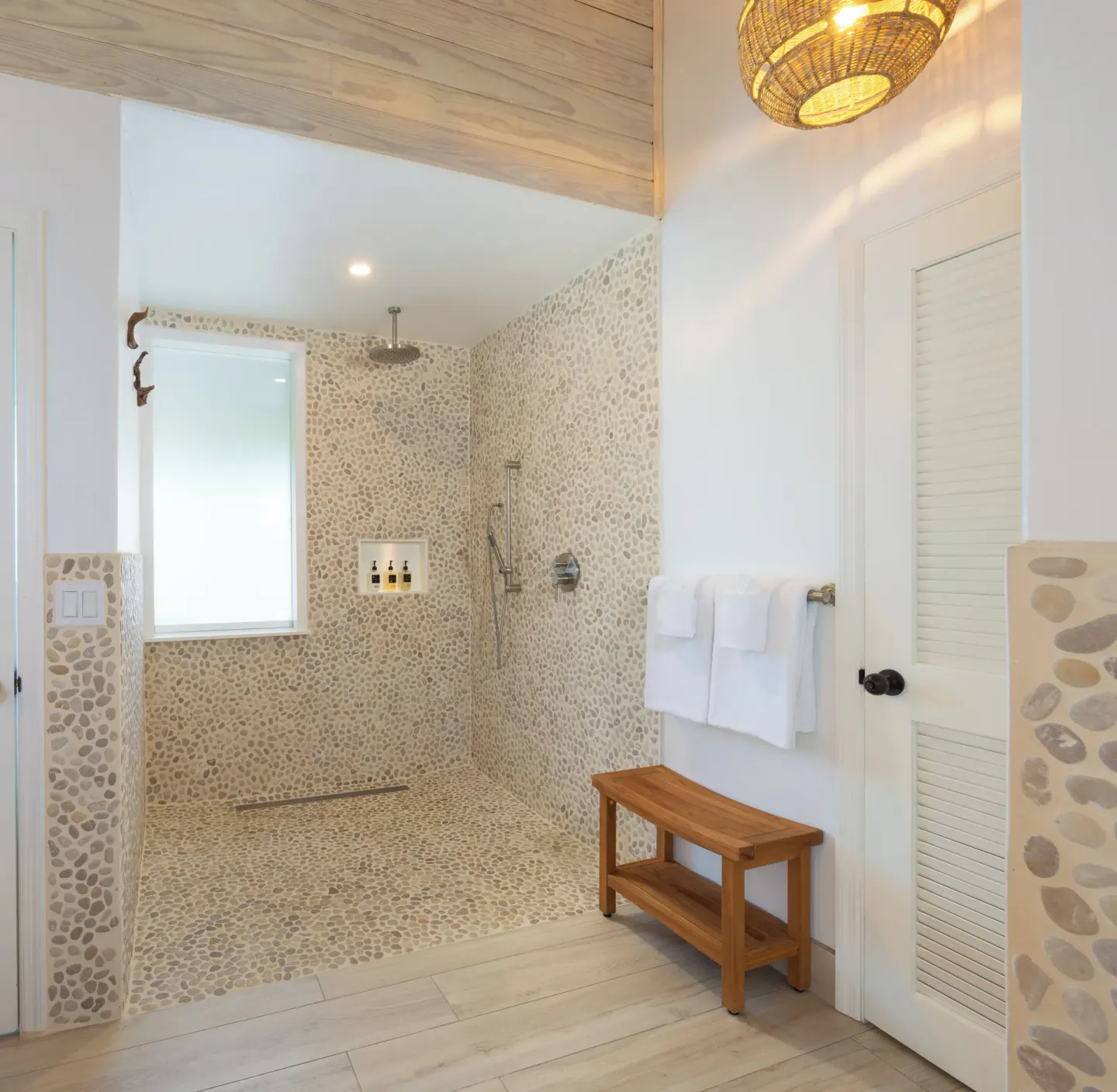 Walk-in pebble-tile shower with towel bench at Galley Bay Resort & Spa.