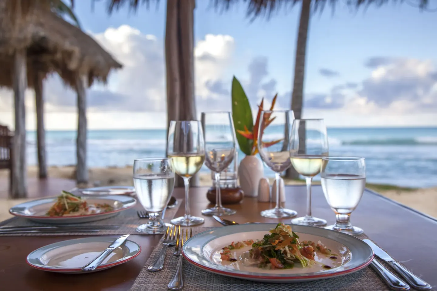 Seaside table with plated dishes and wine at Galley Bay Resort & Spa.