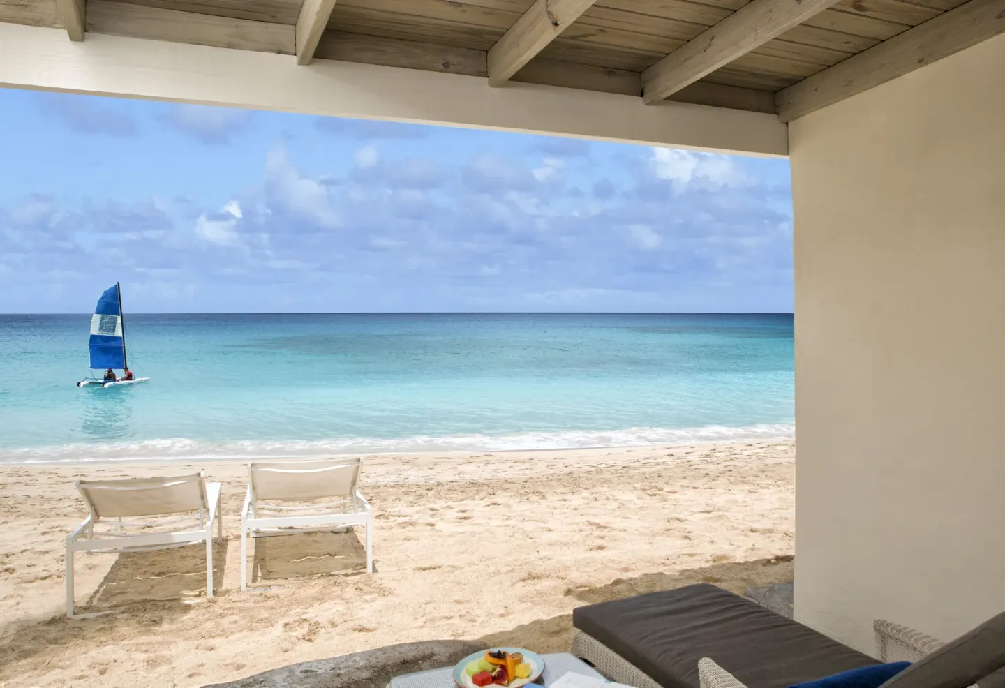 Beachfront terrace with lounge chairs and ocean view at Galley Bay Resort & Spa.