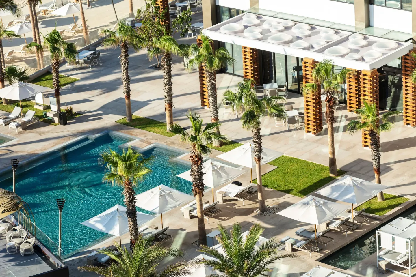 Aerial view of pool courtyards, palms, umbrellas, and terraces at Garza Blanca Los Cabos.