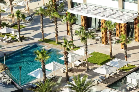 Aerial view of pool courtyards, palms, umbrellas, and terraces at Garza Blanca Los Cabos.