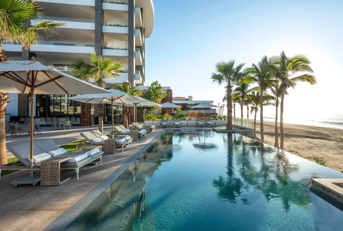 Beachfront infinity pool and shaded loungers at Garza Blanca Los Cabos.