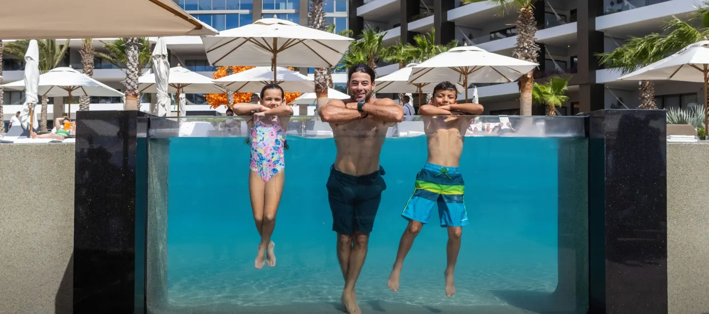 Family leaning on the clear edge of a pool at Garza Blanca Los Cabos.
