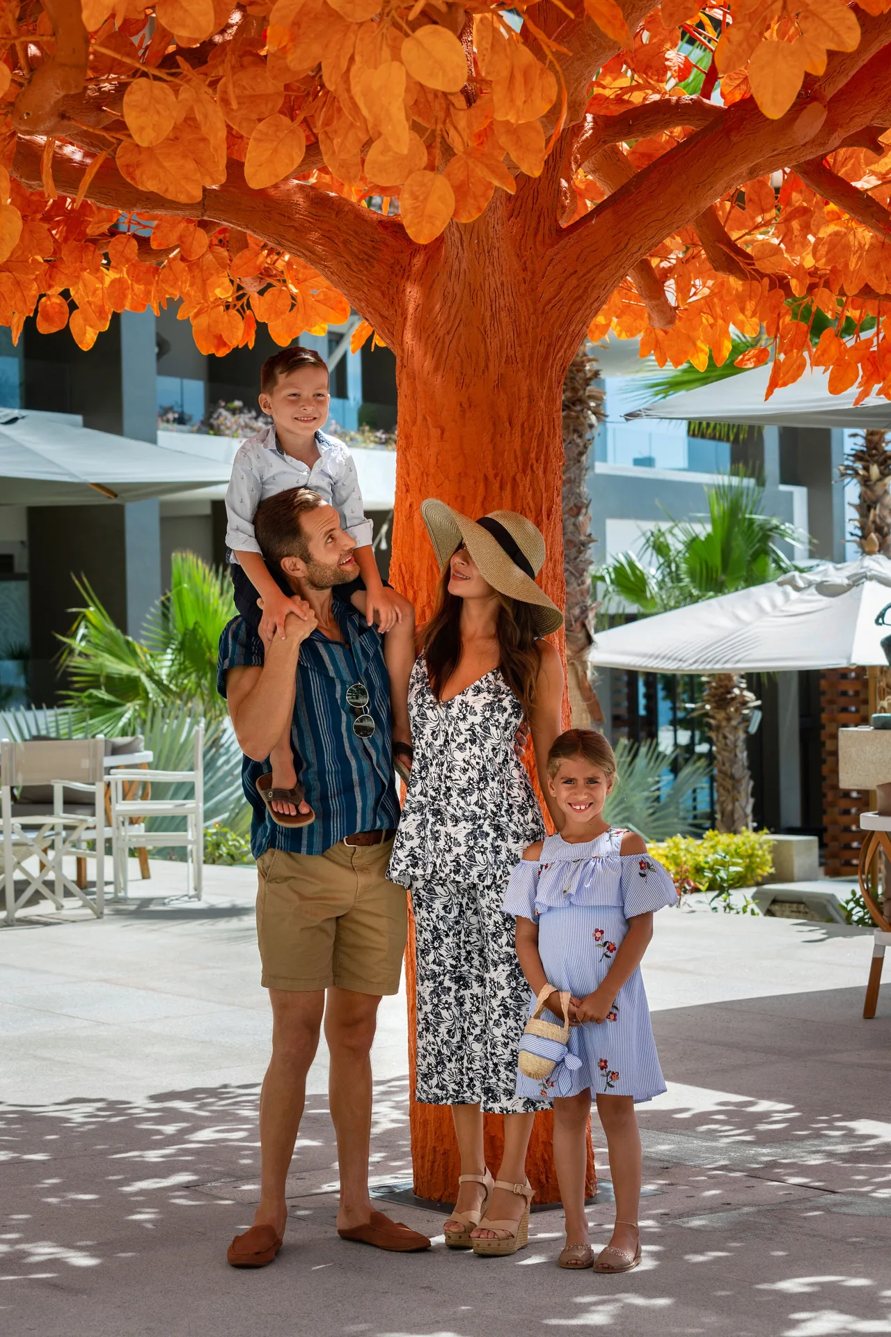 Family posing beneath an orange courtyard tree at Garza Blanca Los Cabos.
