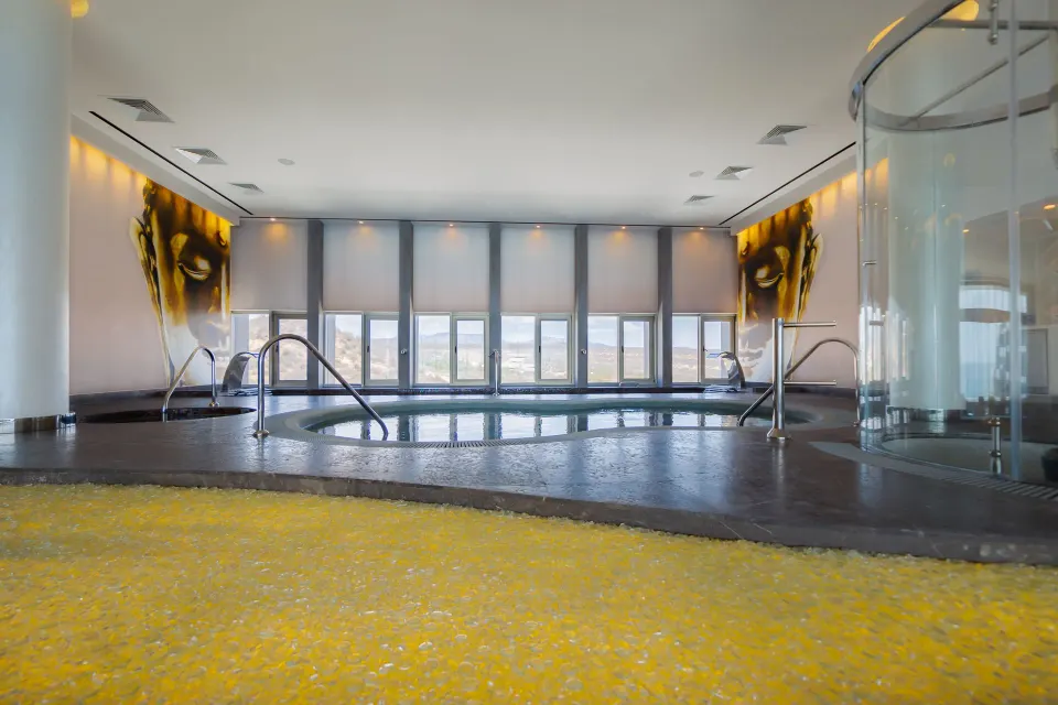 Indoor spa pool with yellow pebble floor and ocean-view windows at Garza Blanca Los Cabos.