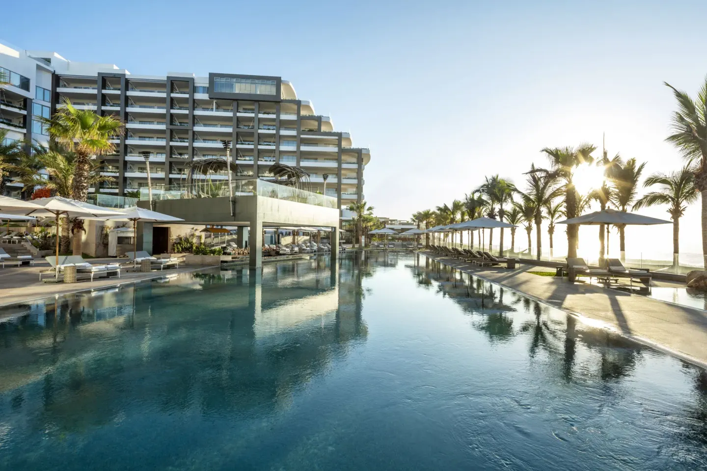 Long pool reflecting palms, umbrellas, and resort tower at Garza Blanca Los Cabos.