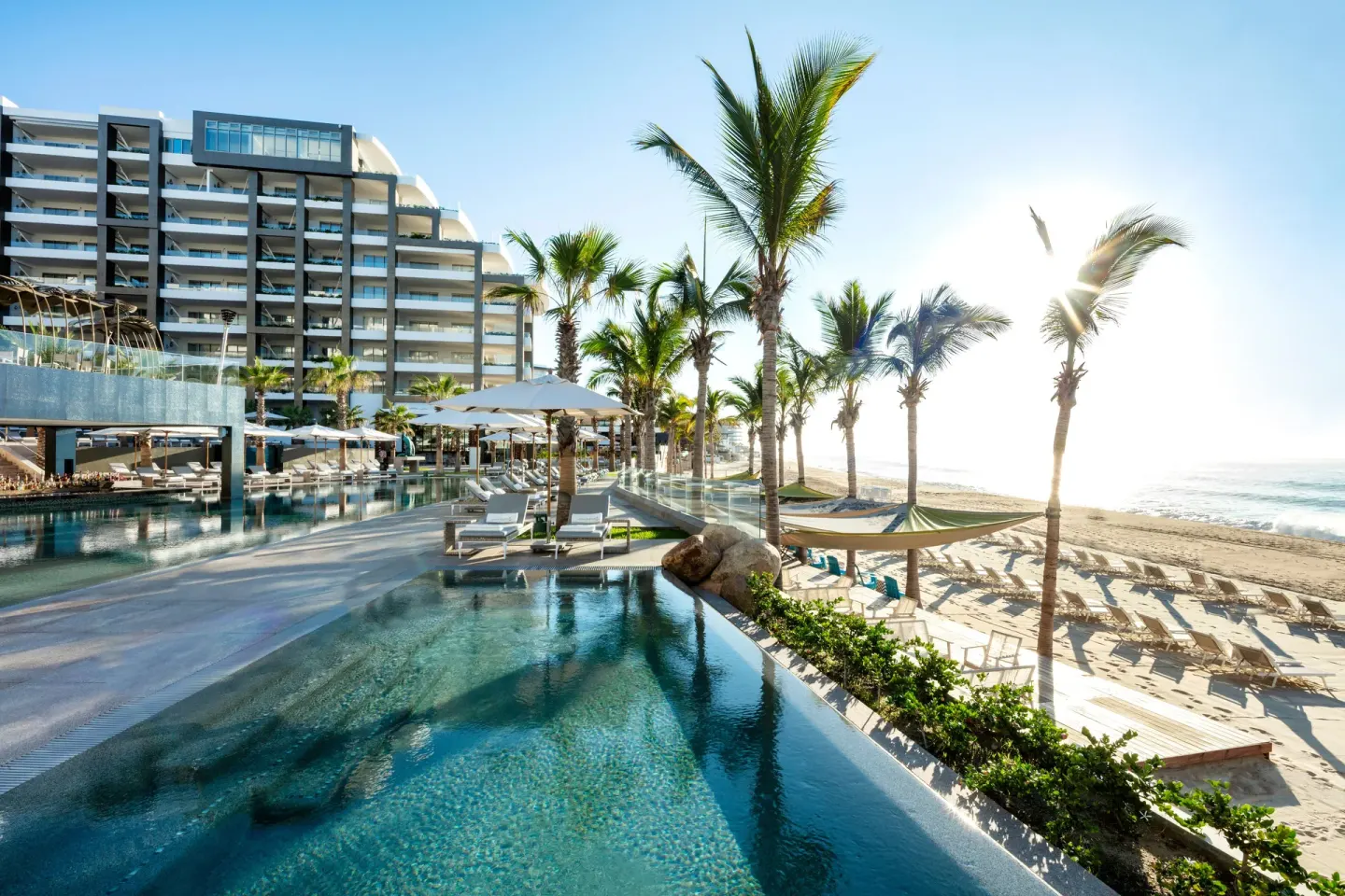 Resort pool, beach, palms, and oceanfront building at Garza Blanca Los Cabos.