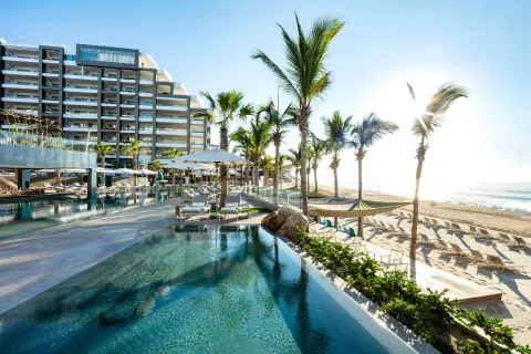 Resort pool, beach, palms, and oceanfront building at Garza Blanca Los Cabos.