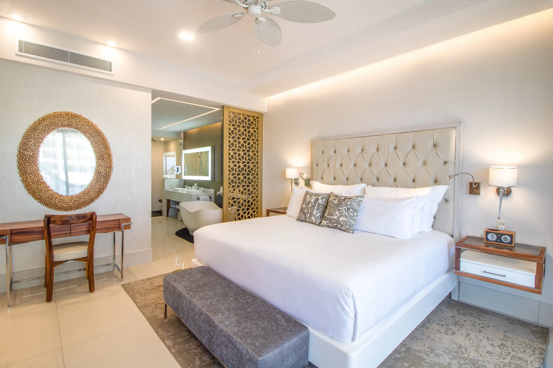 1 Bedroom Suite king bed with tufted headboard and open bathroom at Garza Blanca Los Cabos.