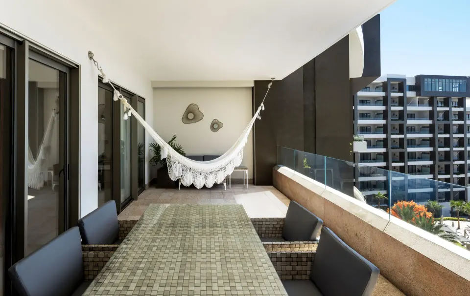 Balcony of the 2 Bedroom Suite King at Garza Blanca Los Cabos with hammock and outdoor dining table.