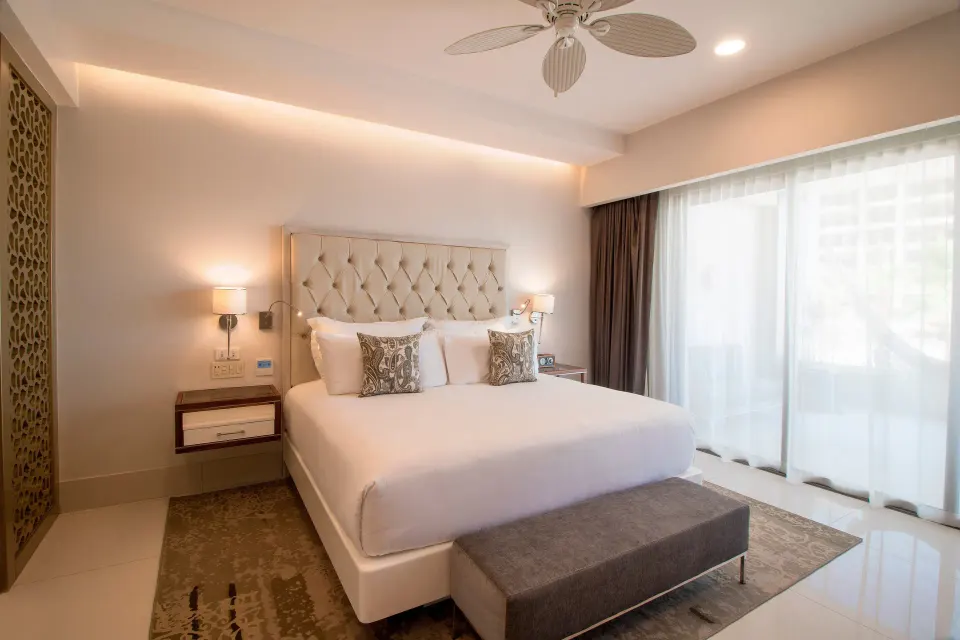 King bed in the 2 Bedroom Suite King at Garza Blanca Los Cabos with tufted headboard and bench.
