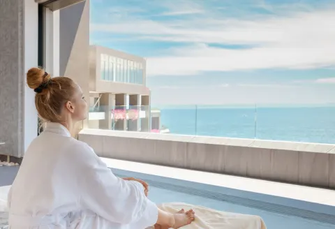 Robe-clad guest seated by an ocean-view balcony at Garza Blanca Los Cabos.
