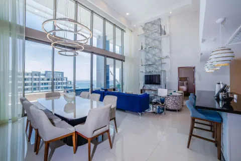 4 Bedroom Loft Ocean View living and dining area at Garza Blanca Los Cabos with tall windows and blue sofa.