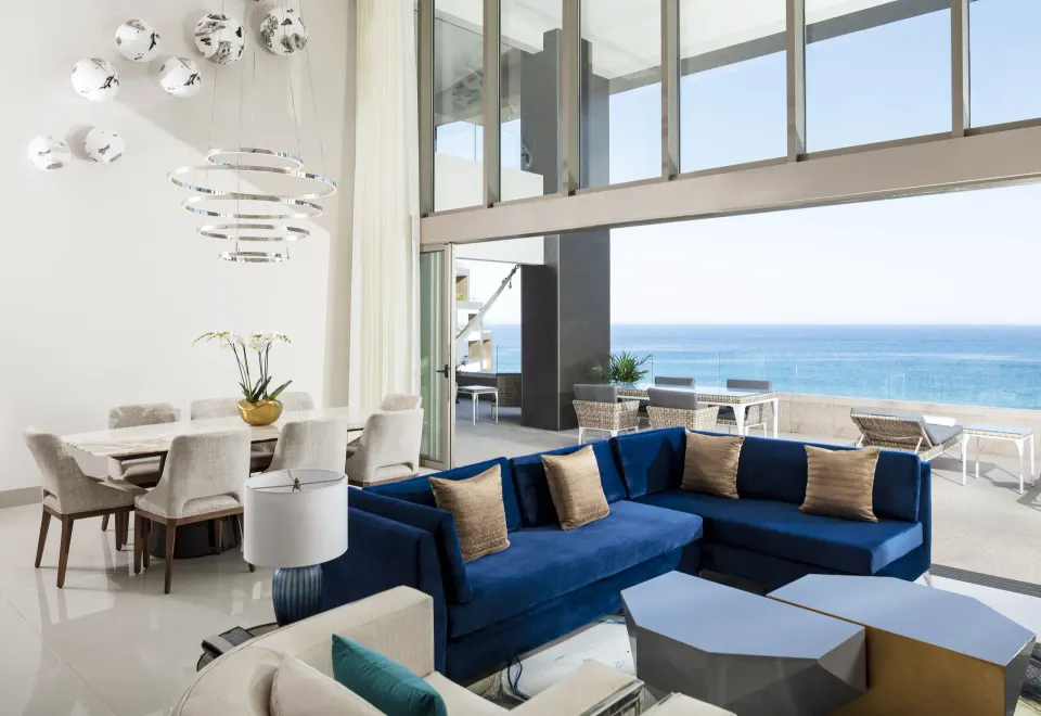 4 Bedroom Loft Ocean View lounge at Garza Blanca Los Cabos with blue sectional, dining table, and ocean view.