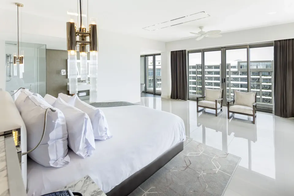 Penthouse bedroom at Garza Blanca Los Cabos with king bed, seating, and balcony doors.