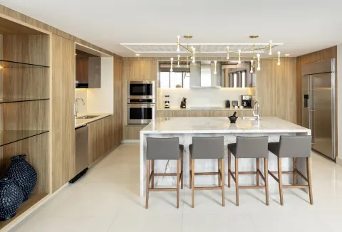 Penthouse kitchen at Garza Blanca Los Cabos with marble island, bar stools, and wood cabinetry.