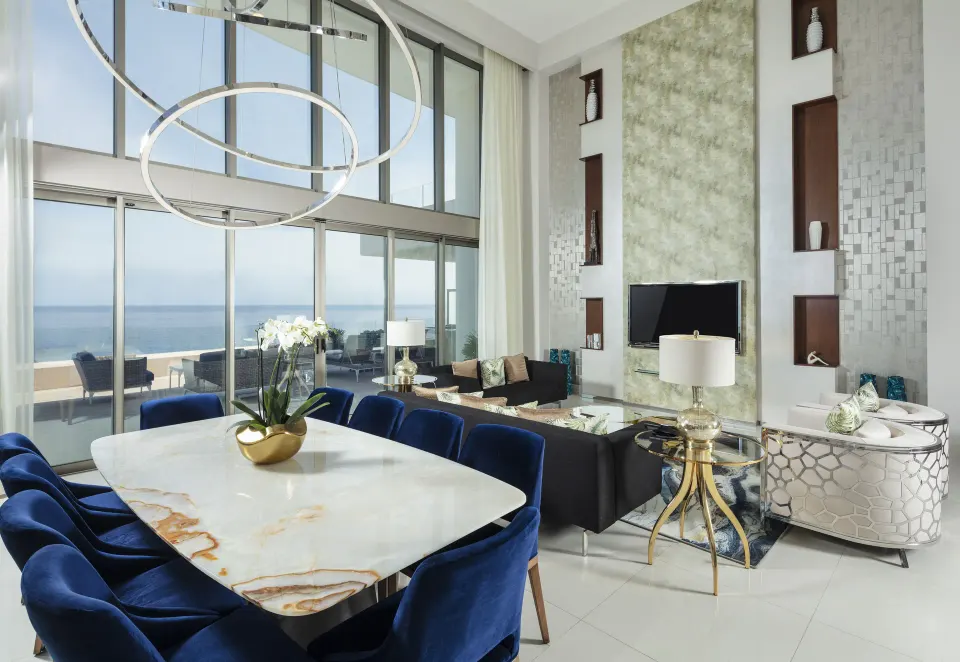 Oceanfront penthouse living and dining room at Garza Blanca Los Cabos with floor-to-ceiling windows.