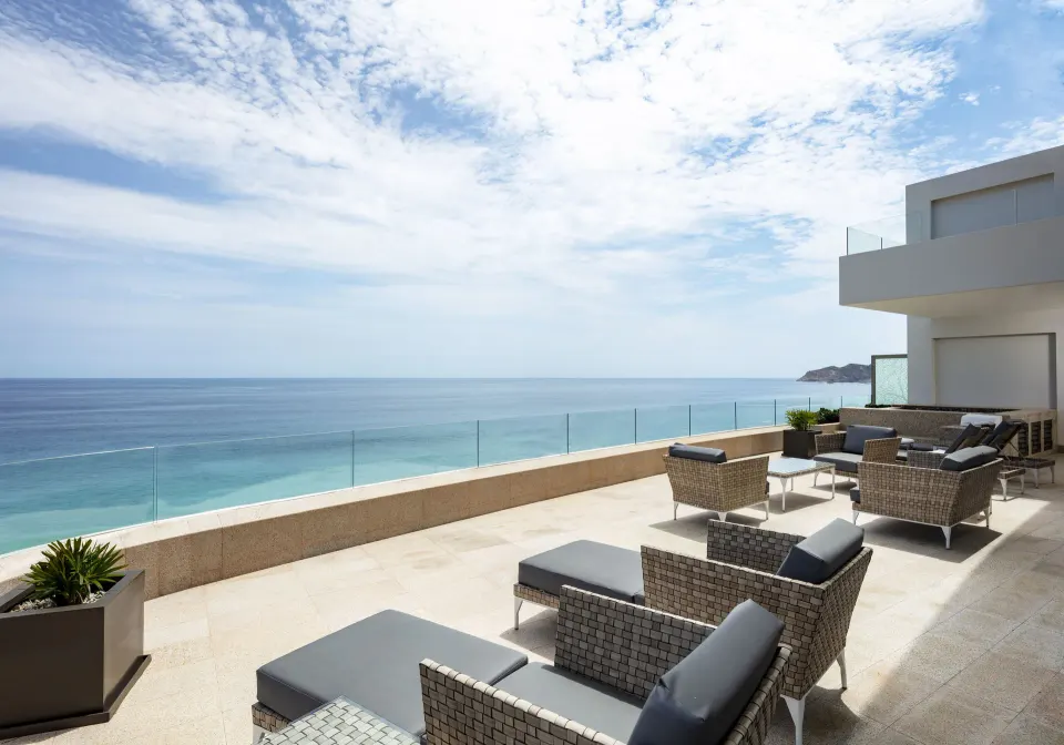 Oceanfront penthouse terrace at Garza Blanca Los Cabos with outdoor seating and glass railing.