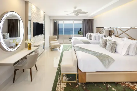 Oceanfront penthouse bedroom with two beds and balcony view at Garza Blanca Los Cabos.