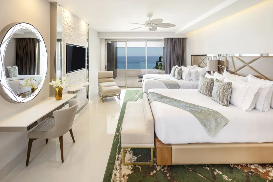 Oceanfront penthouse bedroom with two beds and balcony view at Garza Blanca Los Cabos.