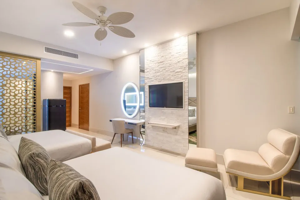 Junior Suite Ocean View with beds, lounge chair, TV wall, and vanity at Garza Blanca Los Cabos.